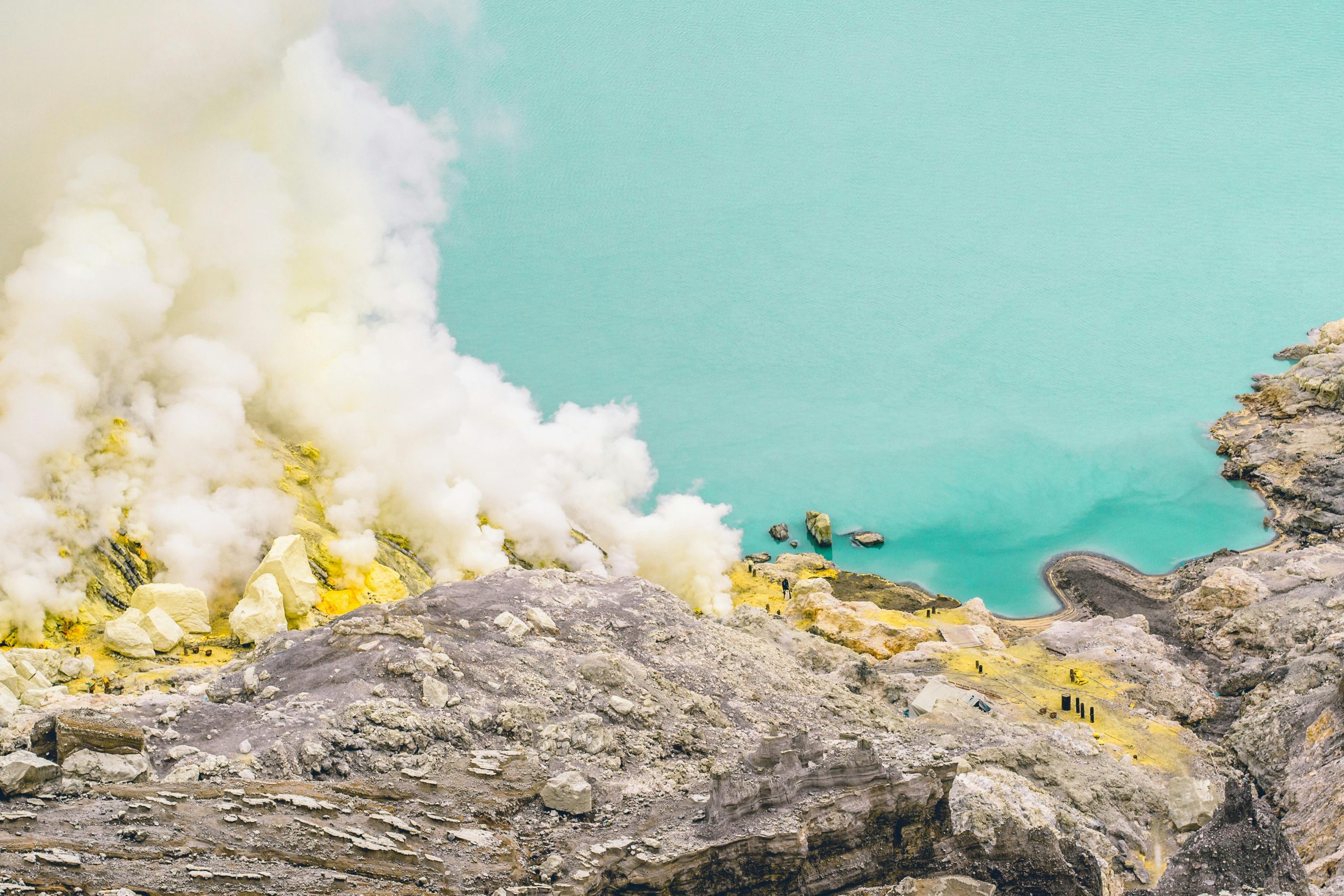 Aerial view of Kawah Ijen's sulfur mine with stunning turquoise lake in East Java, Indonesia.